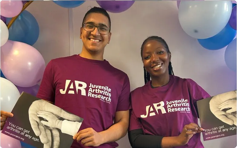 Two PHP team members in Juvenile Arthritis Research t-shirts holding awareness posters