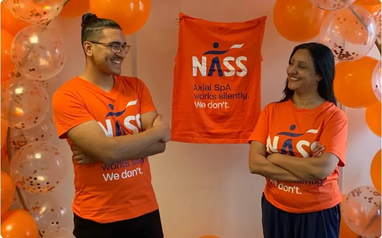 Two PHP team members in orange NASS t-shirts beside a NASS banner