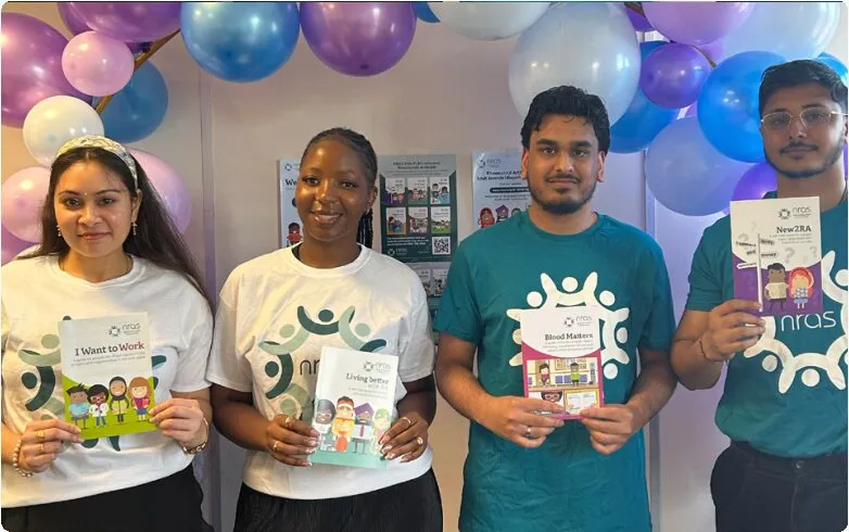 PHP team members holding NRAS leaflets in front of balloons
