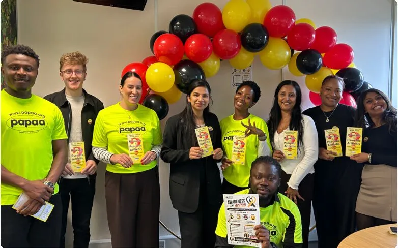 PHP staff and PAPAA representatives in yellow t-shirts holding leaflets in front of a balloon arch