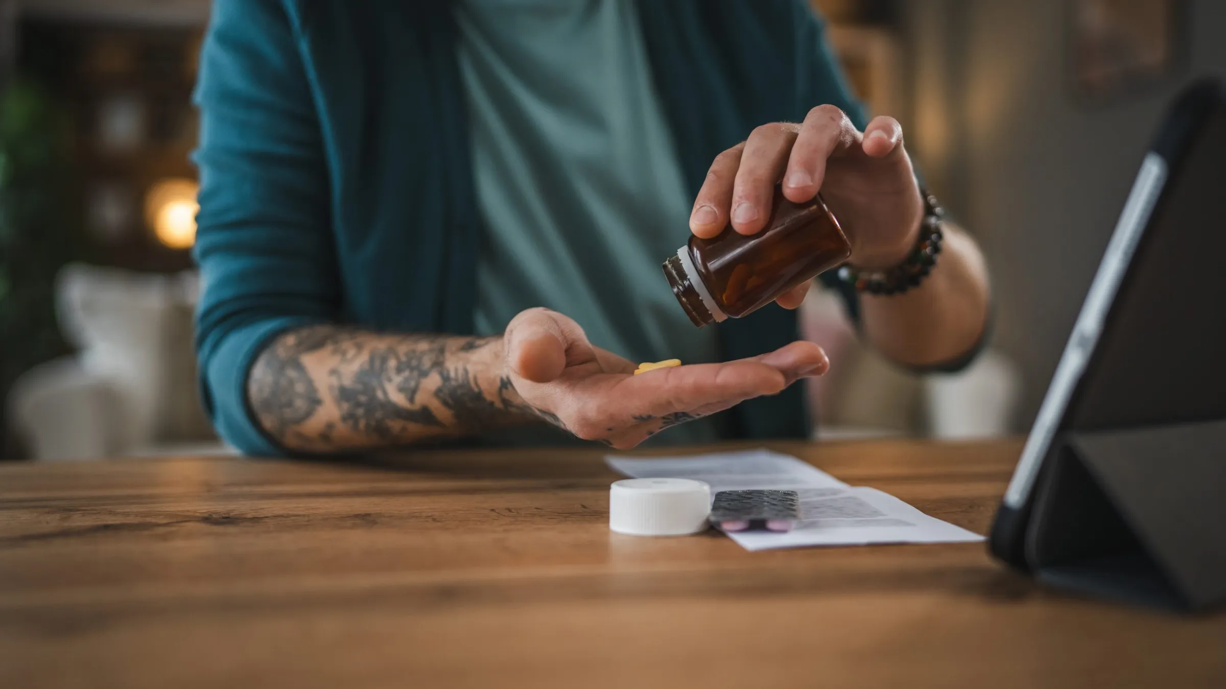 A patient at home tipping a tablet from a medicine bottle into his hand