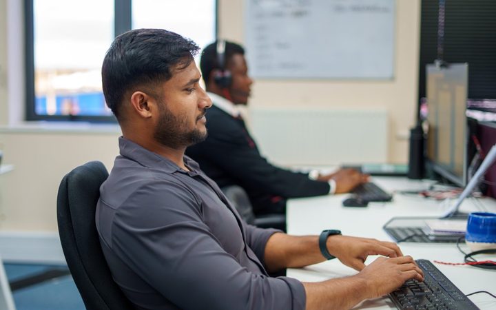 Two Personal Homecare Pharmacy colleagues working at their desks, one on a call
