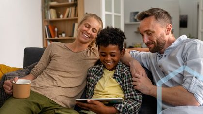A family sitting together on a sofa, looking at a tablet