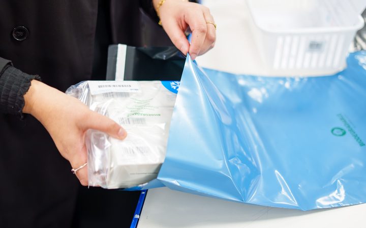 A pharmacy team member sealing a cold-chain medication pack into a delivery bag