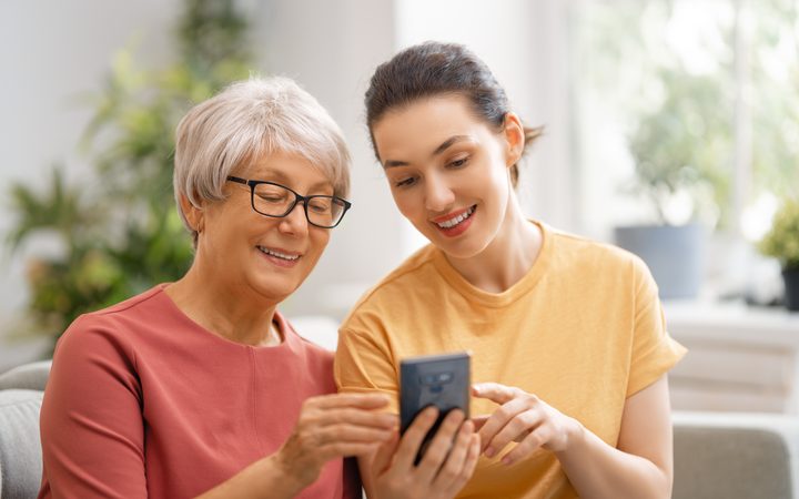 A younger and an older woman smiling at a smartphone together