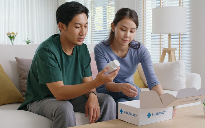 A couple on a sofa at home opening a pharmacy delivery box